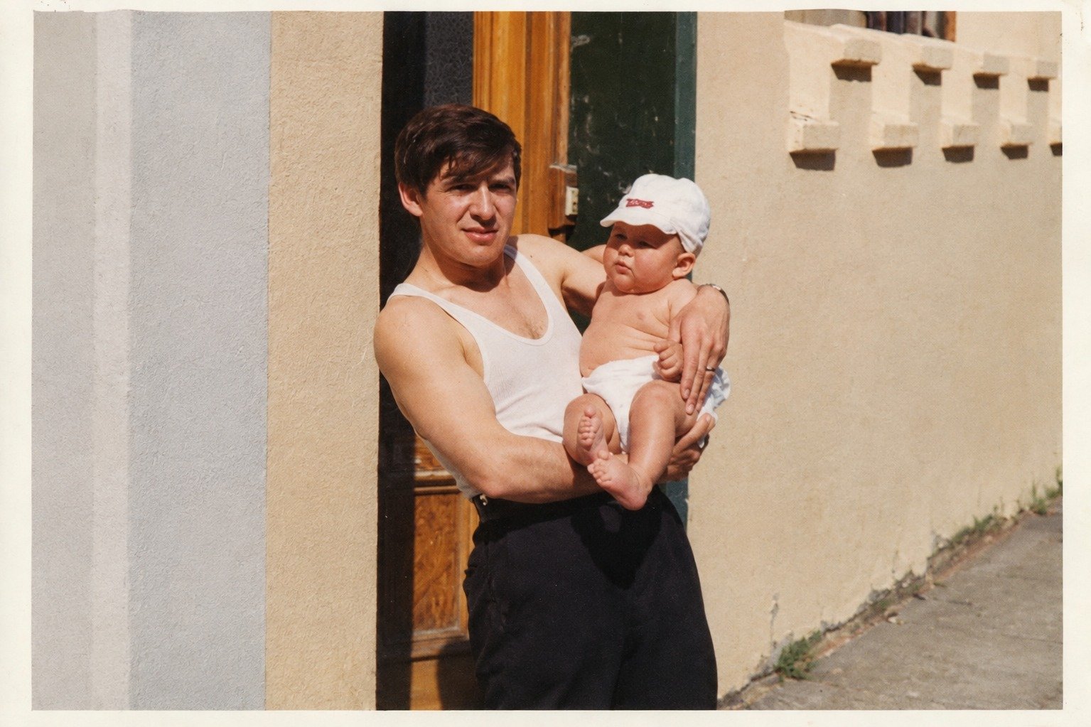 Man holding a baby in a doorway, restored and colour corrected
